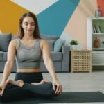Woman sitting cross-legged with closed eyes practicing calm breathing at home