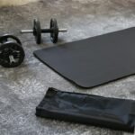 A pair of dumbbells and a black exercise mat on the floor