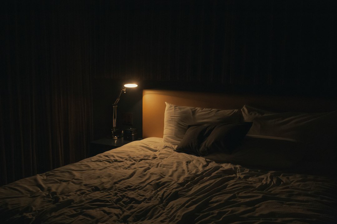 Quiet bedroom with a softly lit table lamp, a calm place to rest with a headache